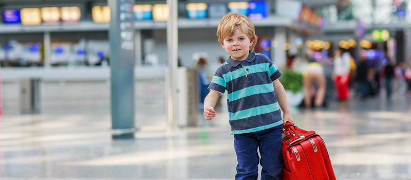 Ребенок тащит чемодан в аэропорту